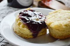 two biscuits with jam on them sit on a plate