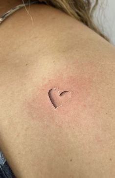 a woman with a small heart tattoo on her back