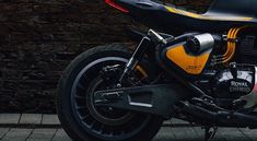 a yellow and black motorcycle parked next to a brick wall