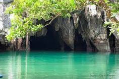 the water is crystal blue and green in this cave like area with trees growing out of it