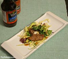 a white plate topped with meat and veggies next to a bottle of beer