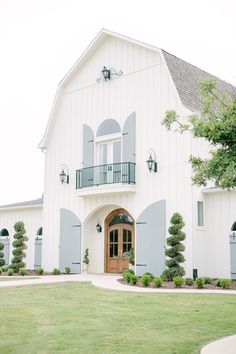 a large white building with blue shutters on the front door and windows in it