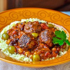 a yellow plate topped with meat and vegetables on top of couscouse rice