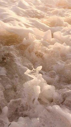 an orange fire hydrant sitting in the middle of some icey water and snow