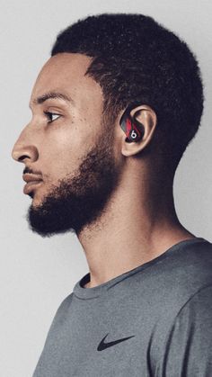 a man with ear buds on his ears looking off to the side, in front of a white background