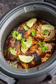 a slow cooker filled with meat and garnished with cilantro sauce