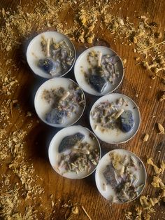 six dishes with food in them sitting on a wooden table next to wood shavings