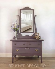 a dresser with a mirror on top of it next to a vase filled with flowers