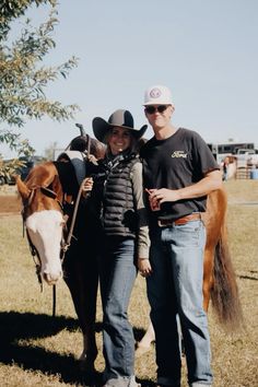 two people standing next to a brown and white horse