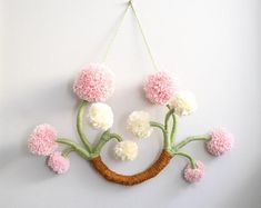 a wall hanging with pom - poms on it and a tree branch in the middle