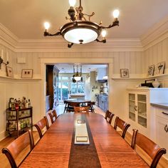 a large wooden table sitting in the middle of a room with lots of chairs around it