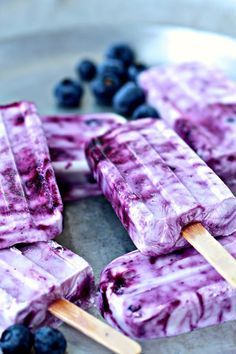 blueberry ice cream popsicles on a metal tray with fresh blueberries around them