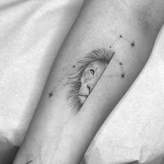 a lion tattoo on the left inner forearm and foot, with stars in the background