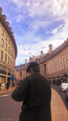 a man standing on the side of a road next to tall buildings