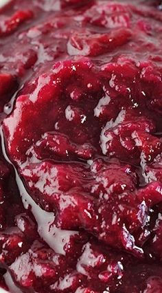 a close up of a bowl of food with cranberry sauce on it's surface