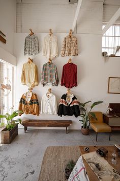 a room filled with lots of clothes hanging on the wall next to a wooden bench