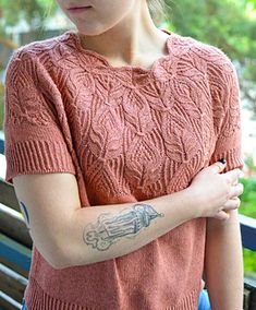 a woman with a tattoo on her arm sitting on a bench