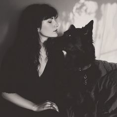 a woman sitting on a couch next to a black dog