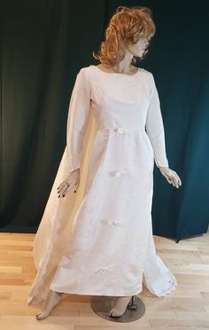 a mannequin wearing a white dress with long sleeves