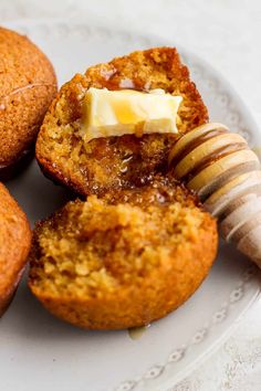 several muffins on a plate with butter and a wooden stick