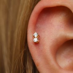 a woman's ear is shown with two small diamond studs on the side