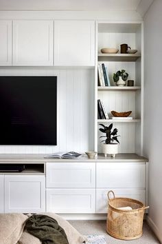 a flat screen tv sitting on top of a white wall mounted entertainment center in a living room