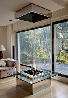 a living room with a fire place in the middle of it and lots of windows