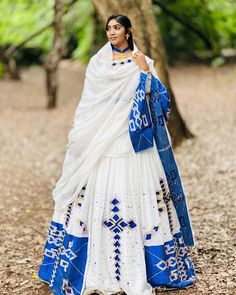 This Habesha Kemis is a true work of art, with its stunning Menen fabric and intricate blue design. The Menen fabric is known for its softness and durability, making this Kemis not only beautiful but also comfortable to wear. The blue design is both striking and delicate, with a pattern that is reminiscent of the intricate designs found in traditional Ethiopian art and textiles. The blue design extends down the front of the Kemis, creating a visually stunning centerpiece that draws the eye and c Blue Bohemian Lehenga With Traditional Drape, Blue Bohemian Traditional Wear For Wedding, Bohemian Blue Traditional Wear For Wedding, Blue Bohemian Wedding Sets, Bohemian Blue Semi-stitched Lehenga, Unstitched Bohemian Blue Lehenga, Bohemian Semi-stitched Blue Lehenga, Bohemian Blue Lehenga With Cutdana, Wedding Kurta With Woven Motifs