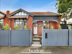 this is an image of a house with a fence in the foreground and trees on the other side