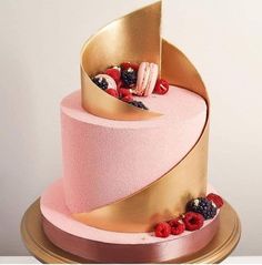 a pink and gold cake with berries on top