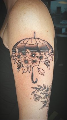 a woman's arm with an umbrella and flowers tattoo design on the left shoulder