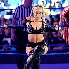 a woman in black and silver outfit standing on top of a wrestling ring