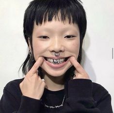 a young woman with braces on her teeth smiles at the camera while holding her hands to her face