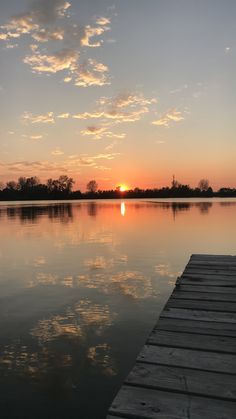 the sun is setting over water with a dock