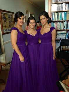 three women in blue dresses posing for the camera with bookshelves in the background