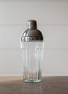 a glass with a metal lid sitting on top of a wooden table