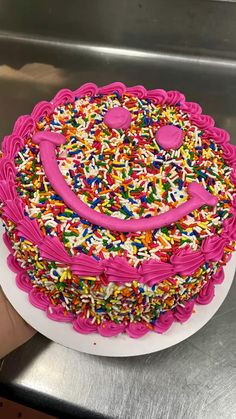 a birthday cake decorated with sprinkles and a smiley face on the top