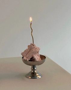 a piece of cake sitting in a bowl with a candle sticking out of the top