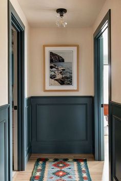 a hallway with dark blue walls and wooden paneling on the wall, along with an area rug