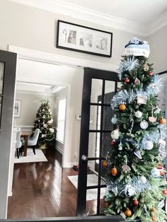 a decorated christmas tree sitting in the middle of a living room next to a doorway