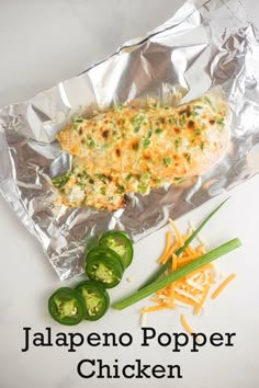 some food is laying on aluminum foil next to green peppers and yellow bell pepper wedges