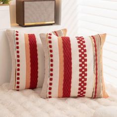 two red and white striped pillows sitting on top of a bed next to a radio