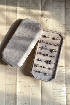 an open box with several pairs of earrings in it sitting on top of a piece of paper