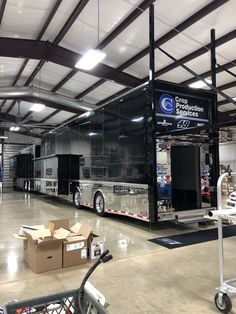 a large black bus parked inside of a garage next to boxes and other items on the floor