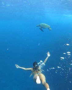 a woman is swimming in the water with a turtle above her head and she has her arms outstretched