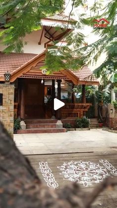 a house with an intricate design painted on the ground and trees in front of it