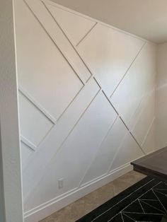 an empty room with white paint on the walls and black rugs in front of it