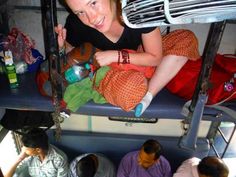 a woman sitting on top of a bunk bed next to other people