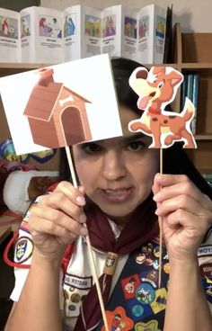 a woman in uniform holding up a cut out of a house with a bear on it