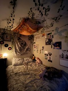 an unmade bed with many pictures on the wall above it and a teddy bear